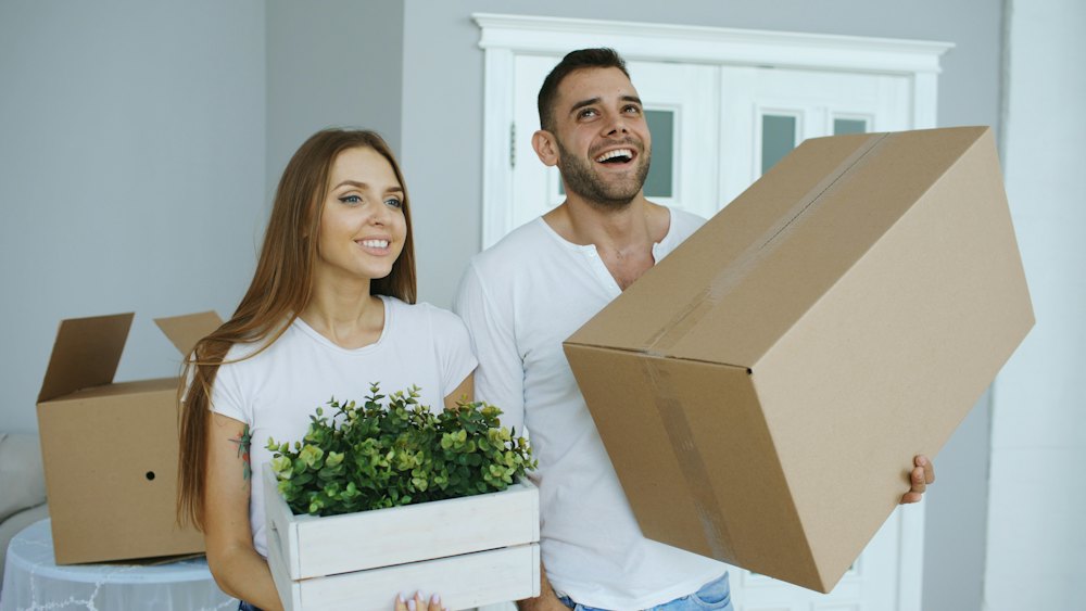 Couple carrying moving boxes into a new home