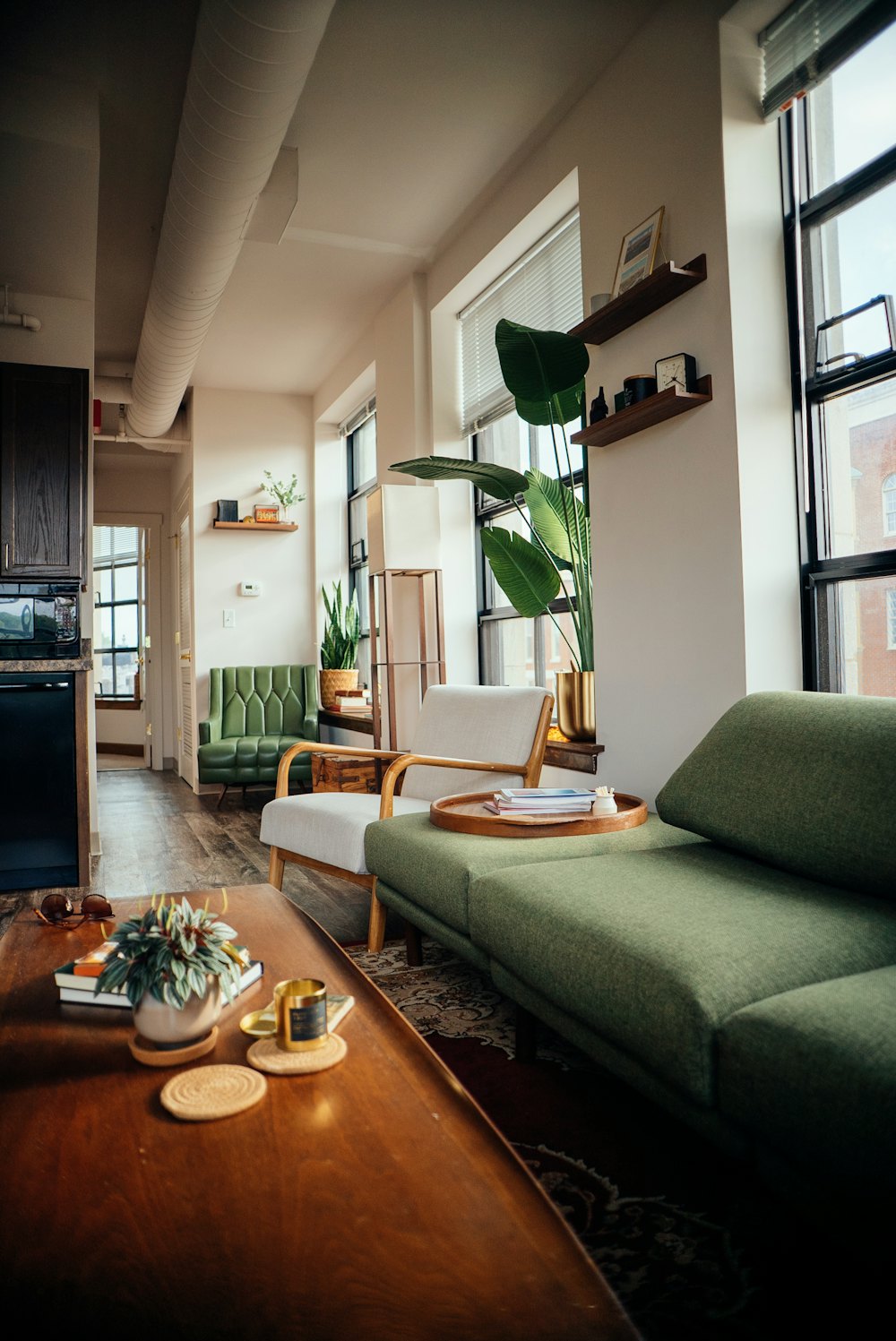 Bright living room of a rental flat with a green sofa and large windows