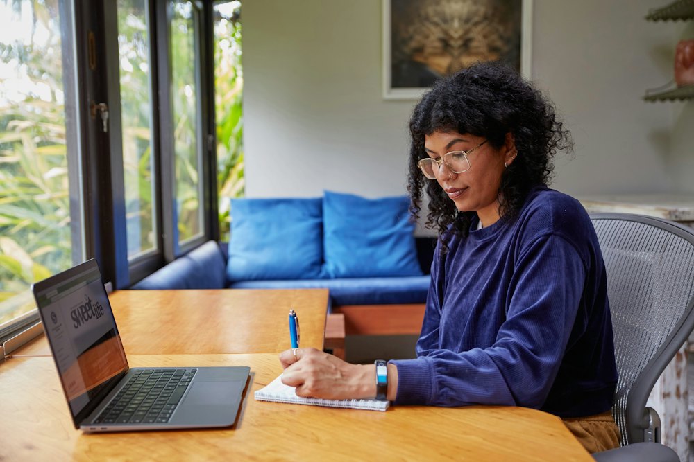 Young woman working on a laptop at home beside a window